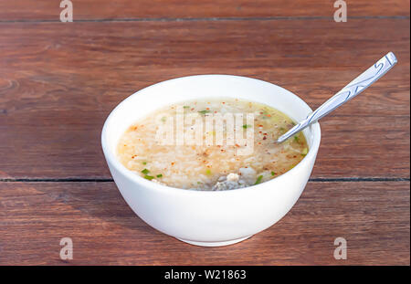 Bollito di maiale in bianco ciotola sul tavolo di legno mangiare la prima colazione. Foto Stock