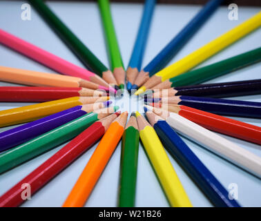 Closeup matite colorate su carta blu sullo sfondo. Macro di un gruppo le matite in un cerchio. Il concetto di business, il lavoro di squadra, gruppo unito Foto Stock