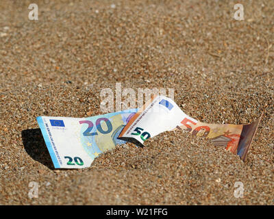 Cinquanta e venti di banconote in euro in sabbia sulla spiaggia con spazio di copia Foto Stock