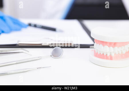 Denti ortodontico modello e professional dentista strumenti sul tavolo in studio dentistico Foto Stock