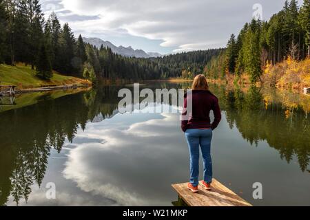 Escursionista femmina sorge su una passerella e si occupa di tutto il lago, autunno a Grubsee, vicino Krun, Karwendel, Alta Baviera, Baviera, Germania Foto Stock