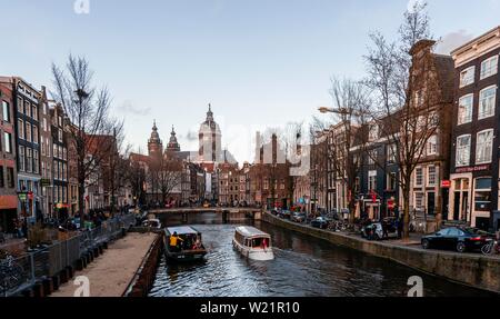 Strada panoramica Oudezijds Voorburgwal al canal con barche, la chiesa di San Nicola in retro, Amsterdam, Olanda Settentrionale, Paesi Bassi Foto Stock