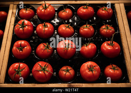 Una inquadratura ravvicinata di un abbondanza di prodotti freschi pomodori rossi sul display a un mercato in stallo. Foto Stock