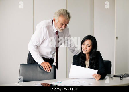 Imprenditori documenti di contenimento per i business partner per discutere e condividere idee ad una riunione di affari e le donne sorridendo felice per il lavoro Foto Stock