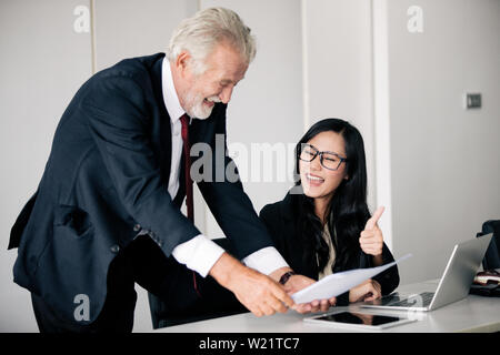 Imprenditori documenti di contenimento per i business partner per discutere e condividere idee ad una riunione di affari e le donne sorridendo felice per il lavoro Foto Stock