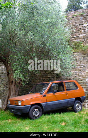 Vintage Fiat Panda parcheggiato a fianco di un antico muro e un albero di olivo. I confini di Firenze vicino al Forte Belvedere. Toscana, Italia Foto Stock