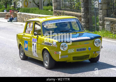 Xix secolo vecchia FIAT 128 auto compete per la gara principale con un paesaggio di campagna intorno alla pista. Foto Stock