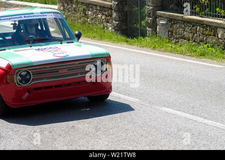 Xix secolo vecchia FIAT 128 auto compete per la gara principale con un paesaggio di campagna intorno alla pista. Foto Stock