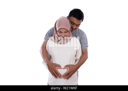 Gesto di coppia del lato rendono forma di cuore sulla pancia in gravidanza con sfondo isolato Foto Stock