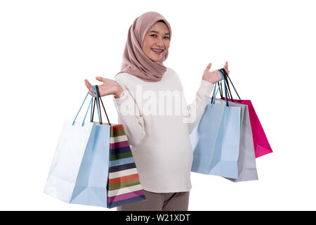 Donna incinta mostra un sacco di borse per lo shopping dopo l'acquisto in un background isolato Foto Stock