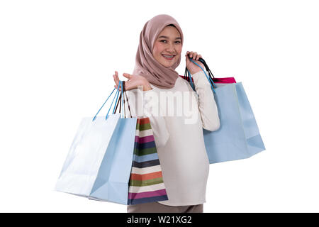 Donna incinta mostra un sacco di borse per lo shopping dopo l'acquisto in un background isolato Foto Stock