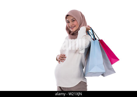 Donna incinta mostra un sacco di borse per lo shopping dopo l'acquisto in un background isolato Foto Stock