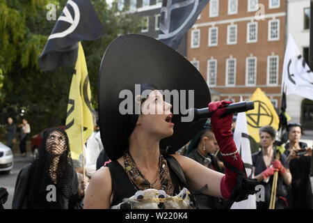 London, Greater London, Regno Unito. 2 Luglio, 2019. Attivista ambientale parla mentre si tiene un microfono durante una manifestazione di protesta a Londra.la ribellione di estinzione gli ambientalisti hanno marciato in un corteo silenzioso denominate " XR Carmen la processione di carbonio'' attraverso il centro di Londra per visitare 5 diversi uffici di petrolio società tra cui ENI, CPCN, SAUDI ARAMCO, Repsol, BP. Hanno fermato presso la sede centrale di olio per dichiarare un 'crime scene'' e consegnare una lettera e copie della XR handbook. Attivista ambientale richiesta da società petrolifere per smettere di esplorare di più combustibili fossili. (Credito mi Foto Stock