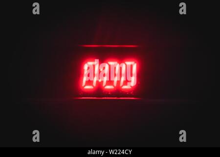 Orologio digitale con numeri al neon rossi "0:00" al buio sfondo che indica mezzanotte Foto Stock