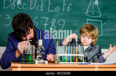 Toccare vive per sempre. Il padre e il figlio a scuola. insegnante uomo con little boy. La scuola le attrezzature di laboratorio. Si torna a scuola. usando microscopio in laboratorio. studente facendo esperimenti scientifici con microscopio in laboratorio. Foto Stock