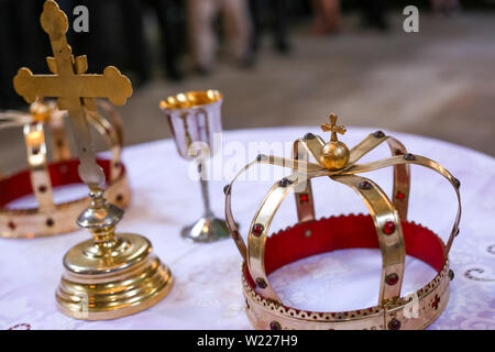 Due corone e croce sul tavolo bianco preparato per il matrimonio. Chiesa ortodossa nozze accessori. Foto Stock