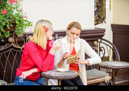 Miglioramento di auto e l'istruzione. Discutendo popolare libro best-seller. Letteratura femminile. Prenota ogni ragazza dovrebbe leggere. Ragazze amici seduti cafe terrazza a bere caffè. La lettura del libro ispiratore. Foto Stock