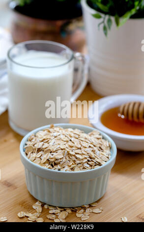 Ciotola di fiocchi di avena con miele e bicchiere di latte Foto Stock