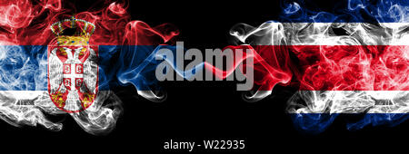 La Serbia vs Costa Rica smoky mystic bandiere poste fianco a fianco. Spessa colorata fumi setosa combinazione di serbo e Costa Rica bandiera Foto Stock