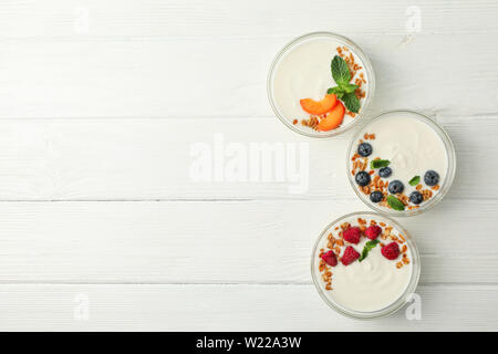 Piano di composizione dei laici con yogurt dessert e ingredienti sul bianco sullo sfondo di legno Foto Stock