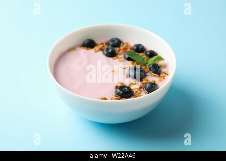 Yogurt con muesli, mirtillo e menta su uno sfondo colorato Foto Stock