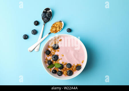 Yogurt con muesli, mirtillo e menta su uno sfondo colorato Foto Stock