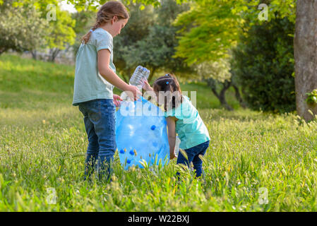 Bambine incassi di bottiglie di plastica a partire da erba. Bambini il prelievo di lettiera nella foresta . Foto Stock