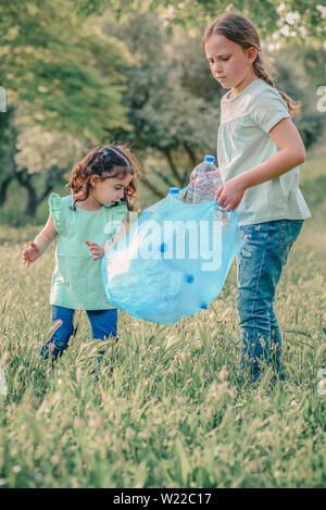 Bambine incassi di bottiglie di plastica a partire da erba. Bambini il prelievo di lettiera nella foresta . Foto Stock