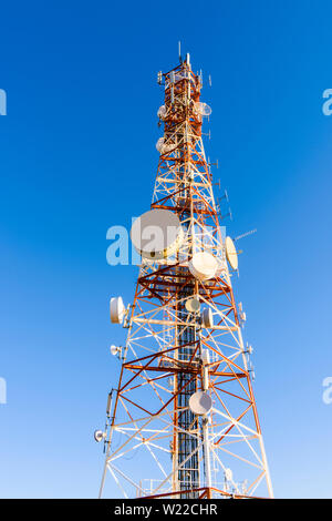 Grandi montante di telecomunicazioni sulla cima di una montagna dipinte di rosso e bianco, e contenente molti piatti microonde, telefono cellulare, antenne a dipoli yagis Foto Stock