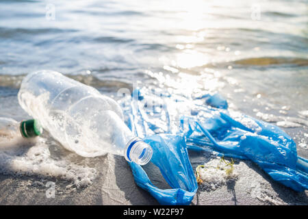 Bottiglie di plastica sulla riva o riva del fiume. Inquinamento delle acque e della natura con rifiuti di plastica. Foto Stock