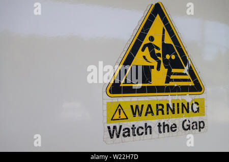 Avvertenza sul lato di lettura del treno guarda il divario. grafica della persona che cade tra il treno e la piattaforma Foto Stock