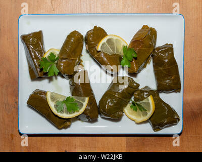 Sarma riempiti o vite ripieni di uva con foglie di limone e prezzemolo come guarnire, tradizionale bagno turco o cucina greca sulla tavola di legno Foto Stock