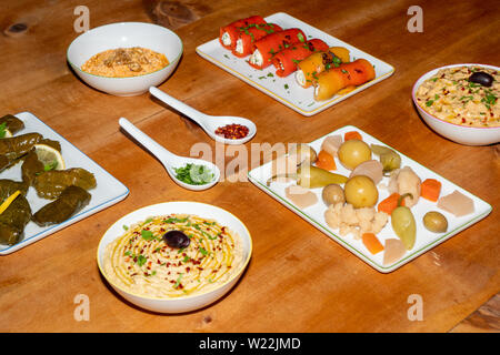 Meze turchi assortiti antipasti su un tavolo di legno - Le foglie di vite ripiene, Involtini di Peperoni, sottaceti, Hummus, Babaganoush Foto Stock