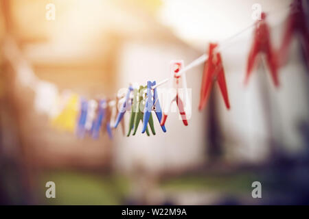 In plastica di colore brillante clothespins appesi a un lungo bianco stendibiancheria nel villaggio presto su una mattina d'estate. Foto Stock