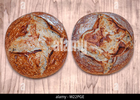 Coppia di due artigiani al forno del pane tradizionale pasta madre casalinga Boule polpettine di pane con crosta su una tavola di legno Foto Stock