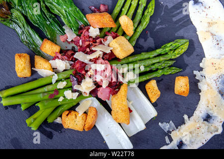 Caesar asparagi con fette di formaggio parmigiano, carne affumicata e crouton cucina gourmet piatto Foto Stock