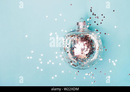Natale sfera trasparente con argento coriandoli su sfondo blu. Concetto di natale. Foto Stock