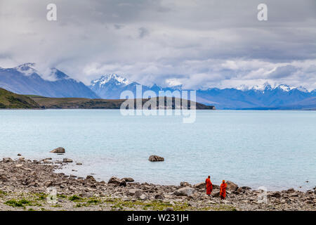 Due monaci buddisti sulla spiaggia al Lago Tekapo, regione di Canterbury, Isola del Sud, Nuova Zelanda Foto Stock