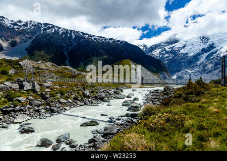 Walkers attraversare un ponte sospeso su il Hooker Valley via, Aoraki Monte Cook, isola del Sud, Nuova Zelanda Foto Stock