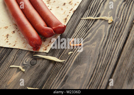 Salsicce affumicate, cavolo e pane pita isolato su sfondo di legno. Foto Stock