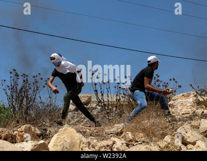 5 luglio 2019 - Qalqilia, Palestina. 05 luglio 2019. Palestinesi manifestanti si scontrano con i soldati israeliani in Cisgiordania città di Kafr Qaddum durante la loro settimanale venerdì protesta contro i contenuti illegali insediamenti israeliani. Alcuni palestinesi pneumatici bruciati e gettava sassi contro le forze israeliane che hanno sparato gas lacrimogeni e rivestito di gomma proiettili ai manifestanti feriti almeno quattro di loro. Dal luglio 2011, i residenti di Kafr Qaddum e i villaggi vicini sono state organizzando manifestazioni di protesta di venerdì contro il prolungamento del vicino insediamento israeliano di Qadumim, la chiusura ai palestinesi del villaggio ma Foto Stock