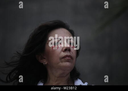 Caracas, Venezuela. 05 Luglio, 2019. Una donna con lacrime di sangue nel make-up prende parte a una prestazione contro il governo del capo di stato Maduro. Il leader dell opposizione e auto-nominato presidente ad interim Guaido aveva chiamato per protesta contro il governo il 5 luglio, giorno di indipendenza del Venezuela. Credito: Rafael Hernández/dpa/Alamy Live News Foto Stock