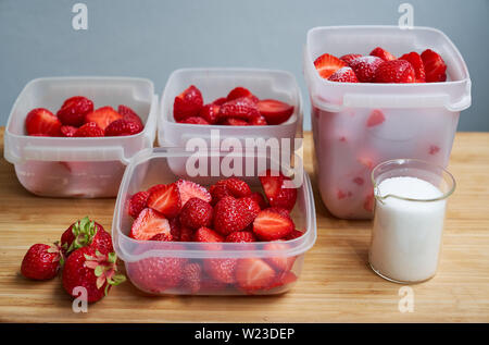 Fragole fresche in scatole di plastica pronto per il congelamento e suger mug sul tavolo di legno Foto Stock