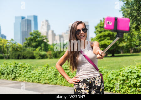 Buon viaggio turistica prendendo Self-portrait foto con il telefono cellulare e selfie stick in una popolare attrazione di New York. Central park donna passeggiate in estate Park di New York City, Manhattan STATI UNITI D'AMERICA. Foto Stock