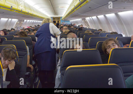 Madrid, Spagna - 13 Giugno 2019: i passeggeri seduti su un aereo durante il volo e hostess nel corridoio - volo Ryanair da Madrid a Milano - sicuramente Foto Stock