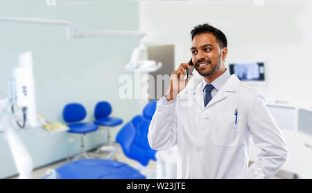 Dentista chiamando sullo smartphone in clinica dentale Foto Stock
