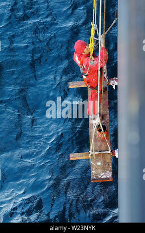 Salvador hahia strade esterna, Brasile - 14 febbraio 2014: un marinaio filippino su una sedia boatswain verniciatura dello scafo di container msc alessia (i Foto Stock