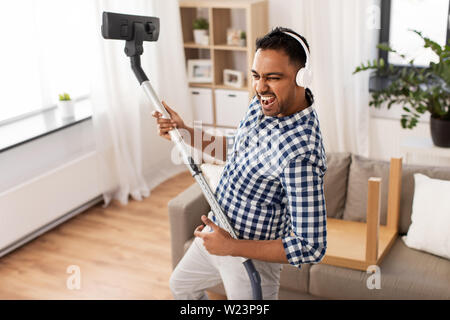 Uomo in cuffie con aspirapolvere a casa Foto Stock