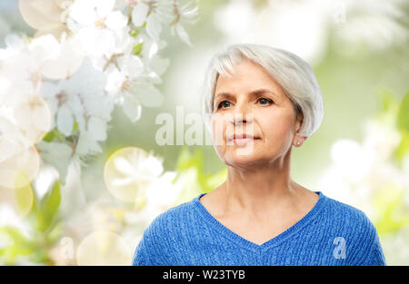 Ritratto di donna senior in maglione blu su grigio Foto Stock