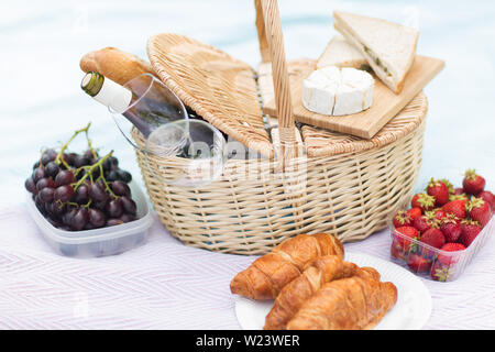 Cesto per pic-nic, cibo e bicchieri di vino sulla coperta Foto Stock